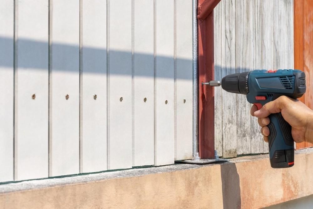 a person is using a drill to install a fence .