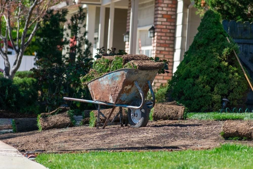 a wheelbarrow filled with dirt is sitting in front of a house .