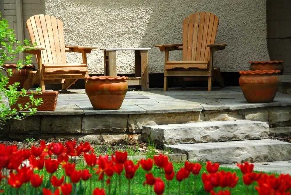 a patio with wooden chairs and potted plants