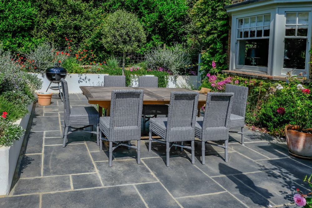 a patio with a table and chairs and a grill