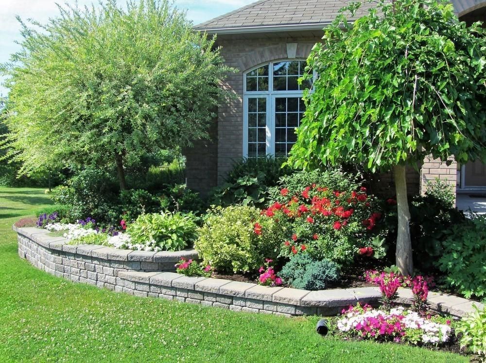 a brick house with a lush green lawn and flowers in front of it .