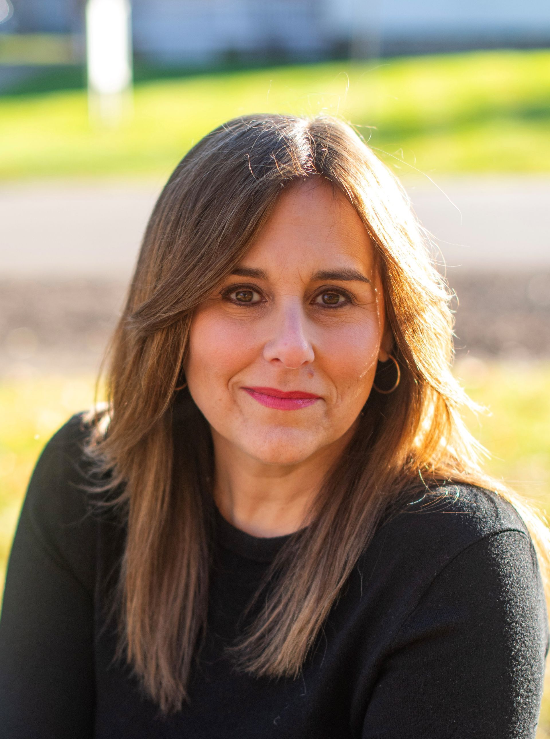 A woman in a black jacket and white shirt is smiling for the camera.