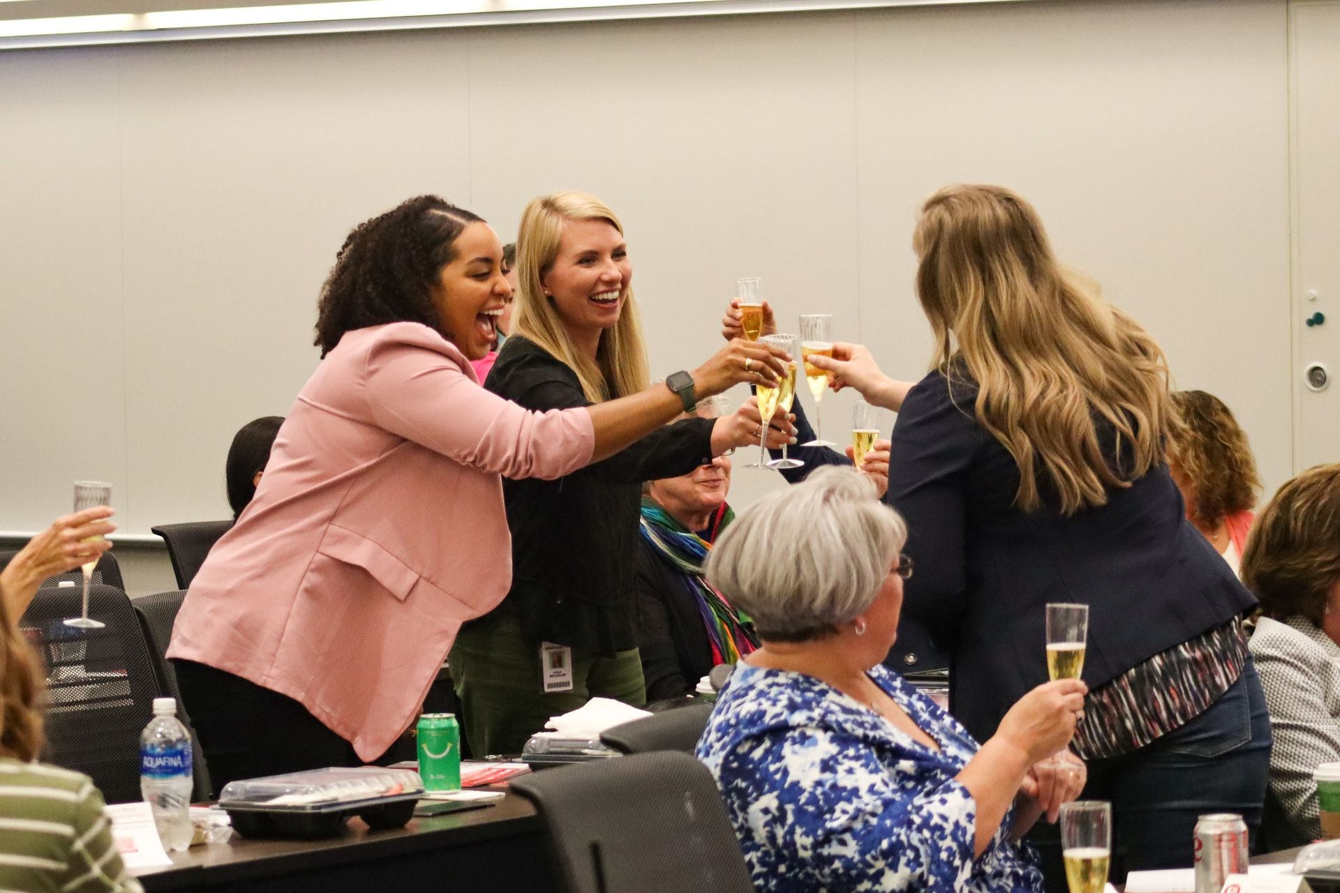 A group of women are toasting with champagne in a classroom.