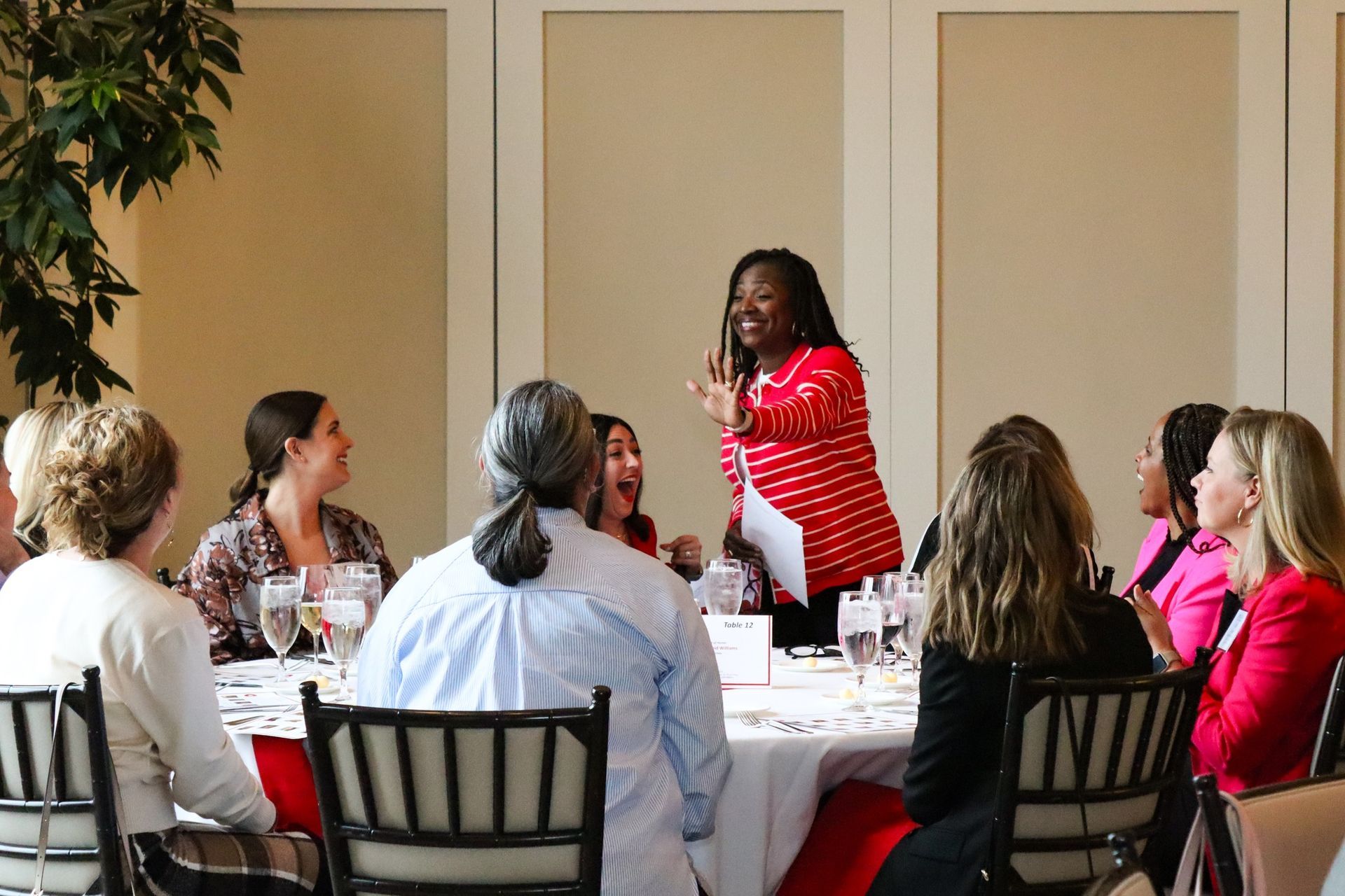 A woman is standing in front of a group of women sitting at a table.