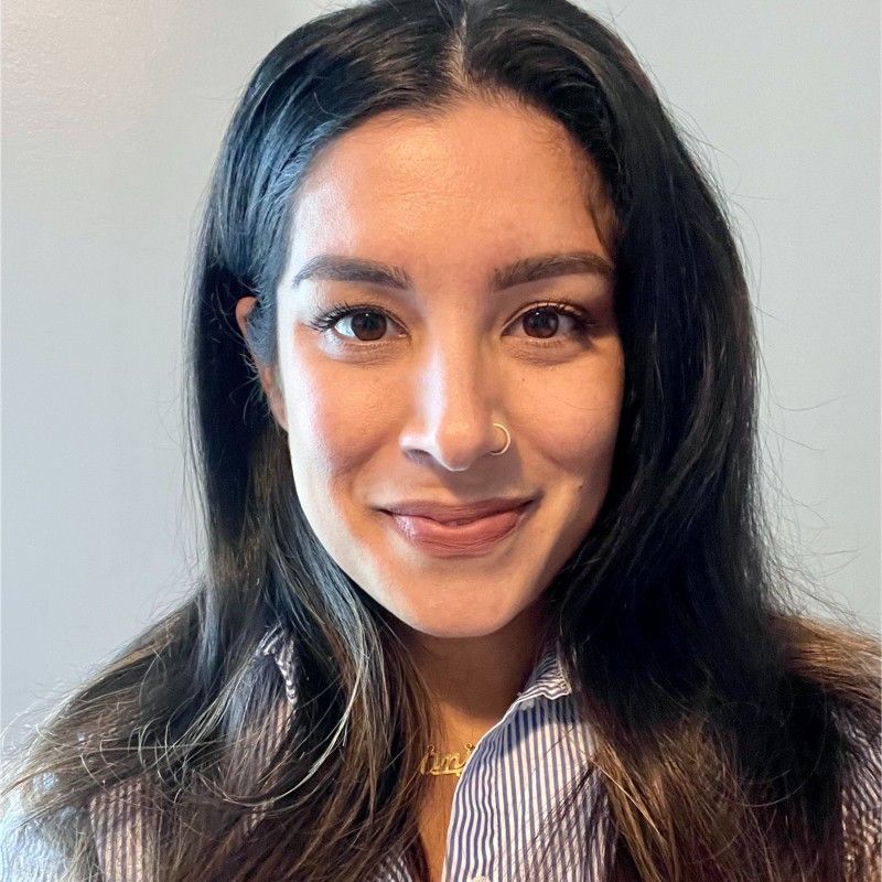 A woman with long hair and a nose ring is smiling for the camera.