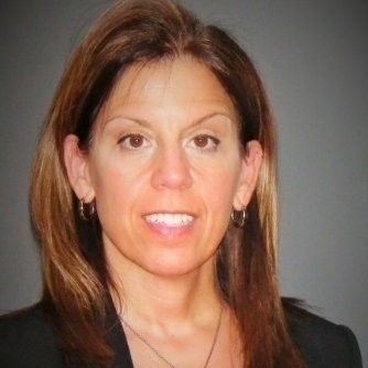 A woman wearing a black jacket and earrings is smiling for the camera.