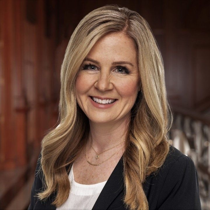 A woman with long blonde hair is smiling for the camera