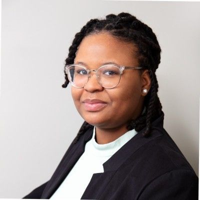 A woman wearing glasses and a black jacket is smiling for the camera.