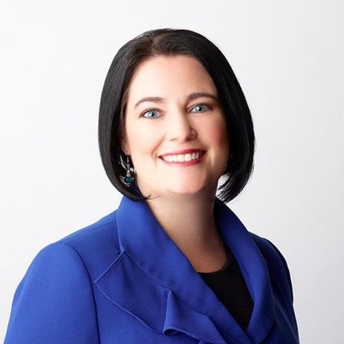 A woman in a blue jacket is smiling for the camera.