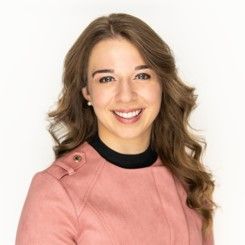 A woman in a pink jacket is smiling for the camera.