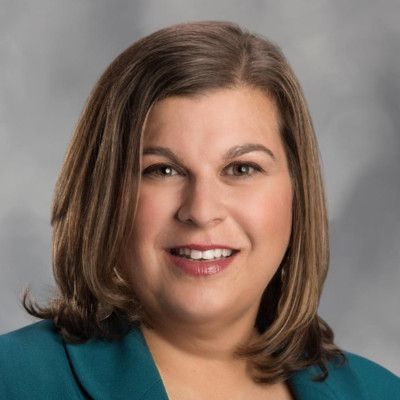 A woman in a blue jacket is smiling for the camera.