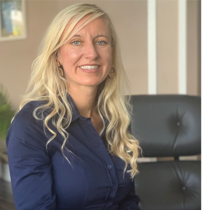 A woman in a blue shirt is sitting in a chair and smiling.