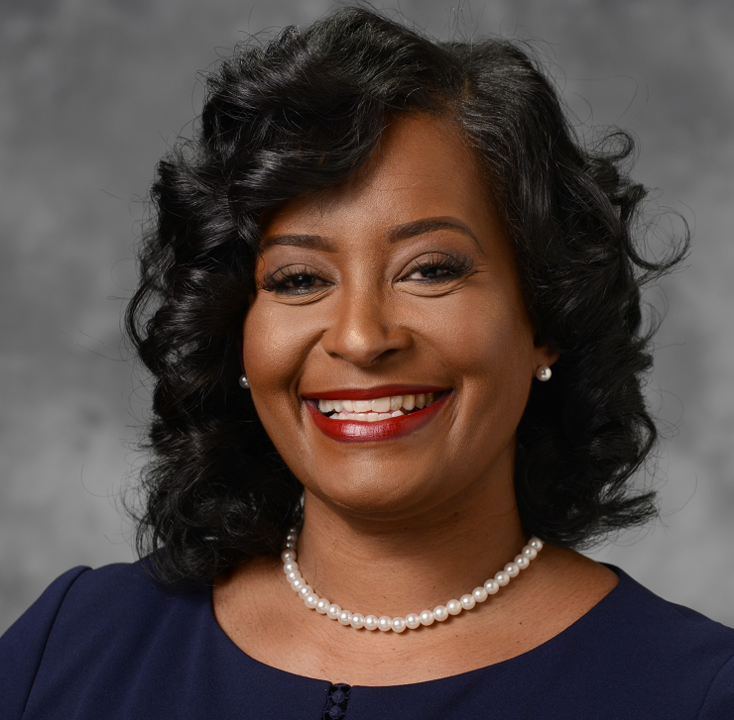 A woman wearing a pearl necklace is smiling for the camera