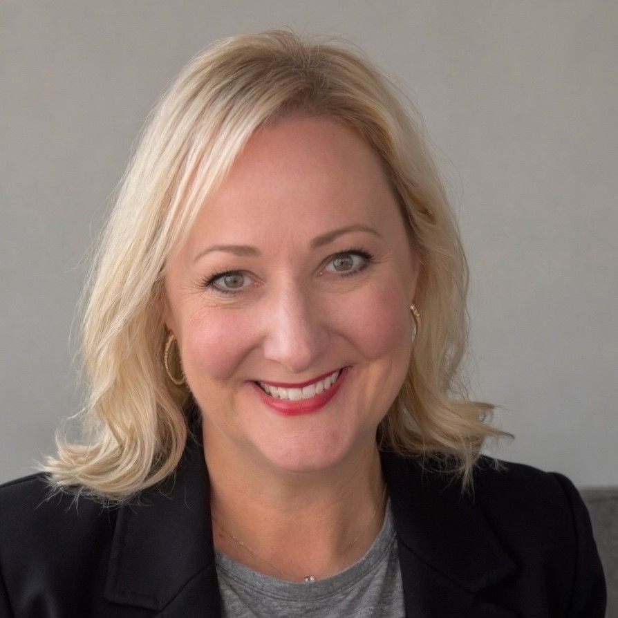 A woman in a white jacket is smiling for the camera.