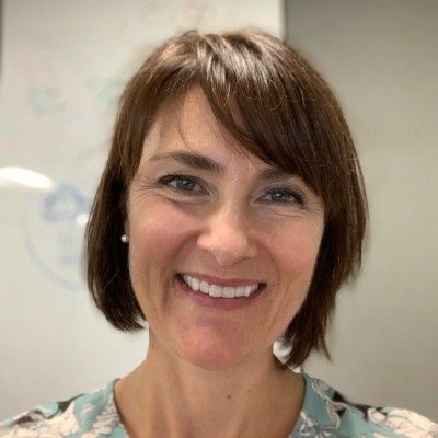 A woman with short brown hair is smiling for the camera.