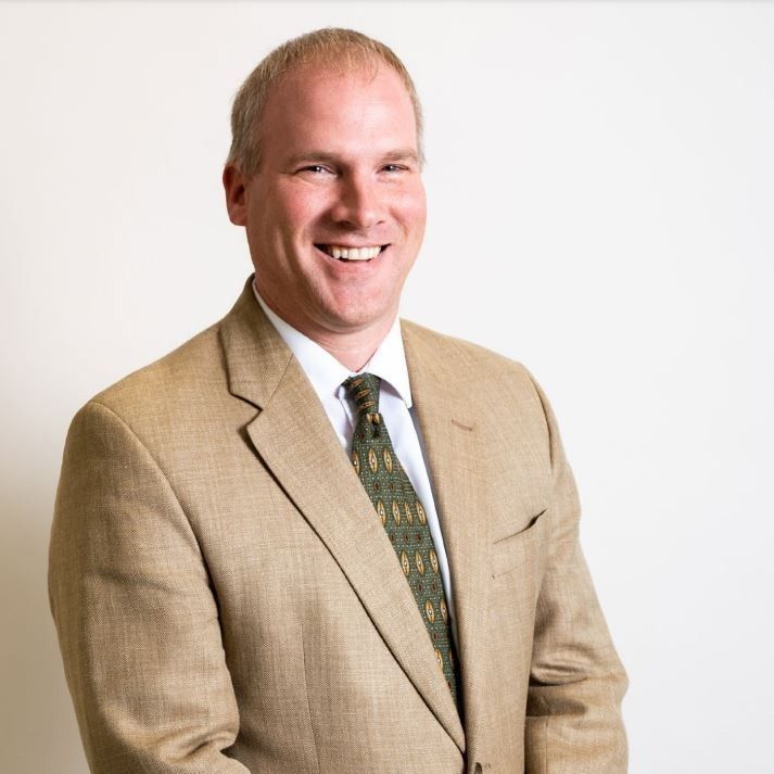 A man in a suit and tie is smiling for the camera