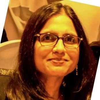 A woman wearing glasses and earrings smiles for the camera