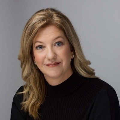 A woman is wearing a black sweater and smiling for the camera.