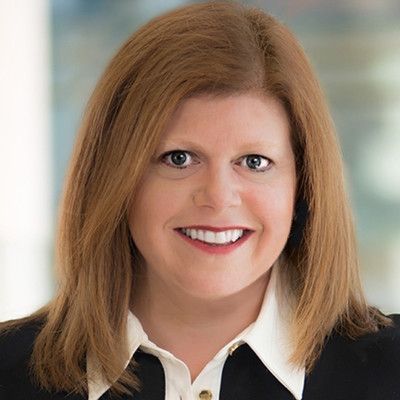 A woman in a black jacket and white shirt is smiling for the camera.