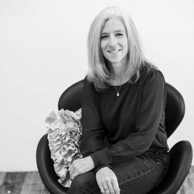 A woman is sitting in a chair with a pillow on her lap.