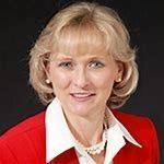 A woman in a red jacket and white shirt is smiling for the camera.