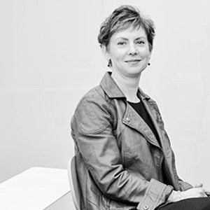 A woman in a leather jacket is sitting in a chair in a black and white photo.