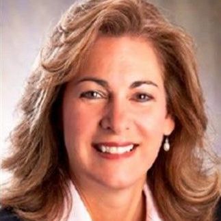 A woman in a suit and white shirt smiles for the camera