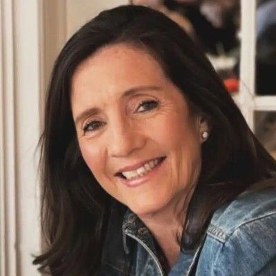 A woman in a denim jacket is smiling for the camera.