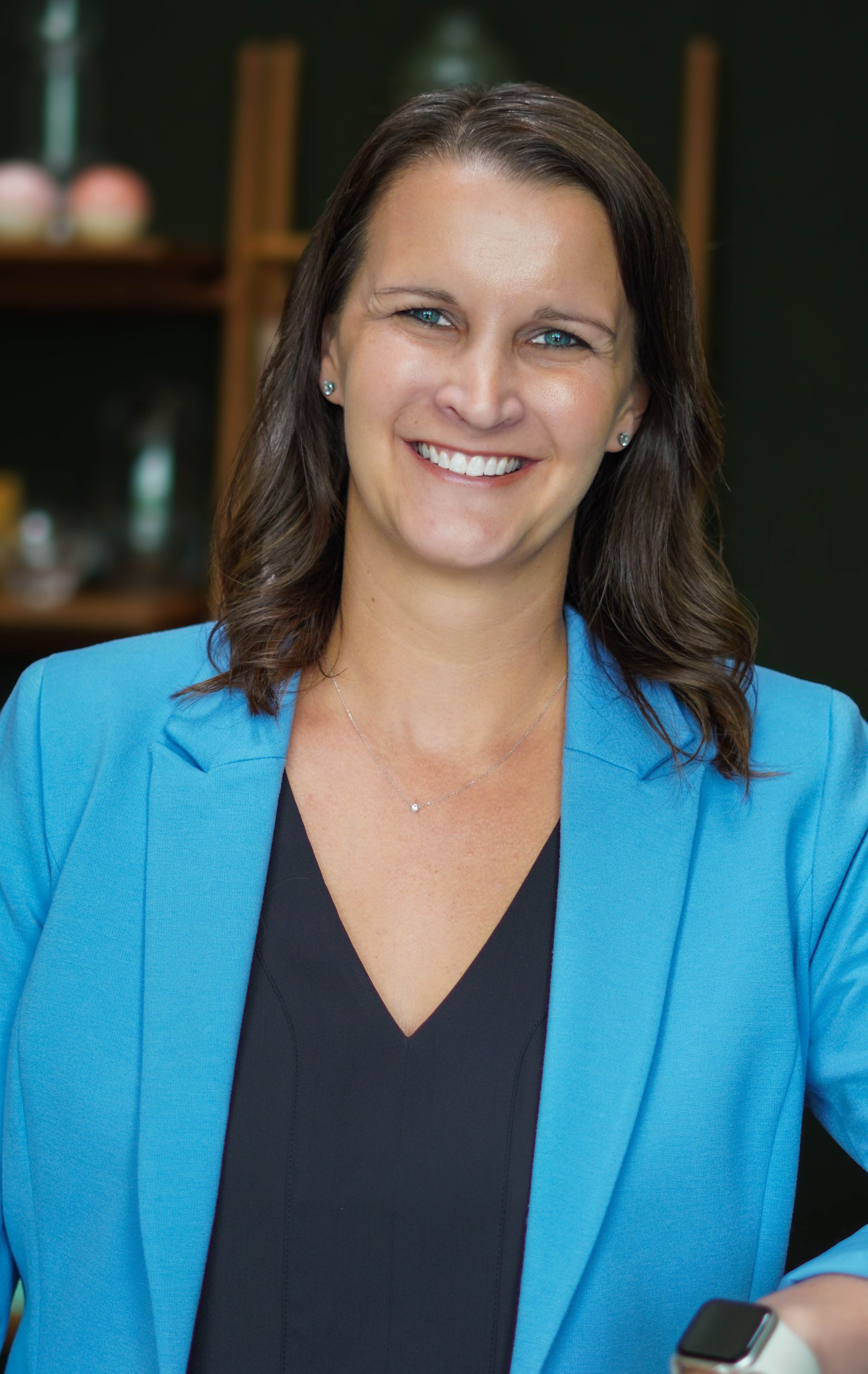 A woman in a green dress is smiling while sitting in a chair