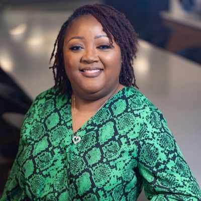 A woman in a green snake print shirt is smiling for the camera.