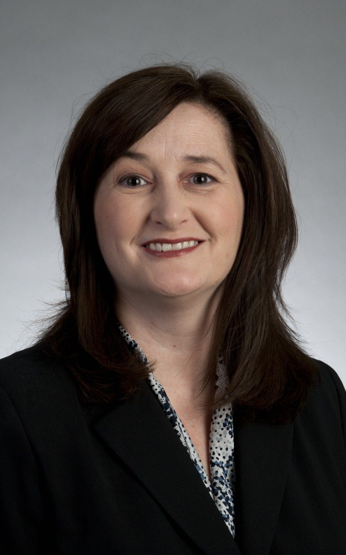 A woman is wearing a black jacket and smiling for the camera.