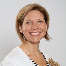 A woman in a white shirt is smiling for the camera.