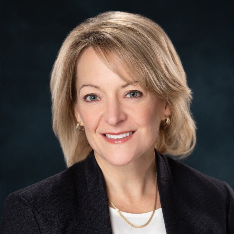 A woman wearing a black jacket and white shirt is smiling for the camera.