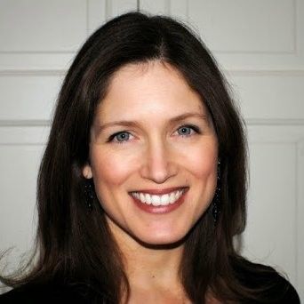 A woman with long brown hair is smiling for the camera.
