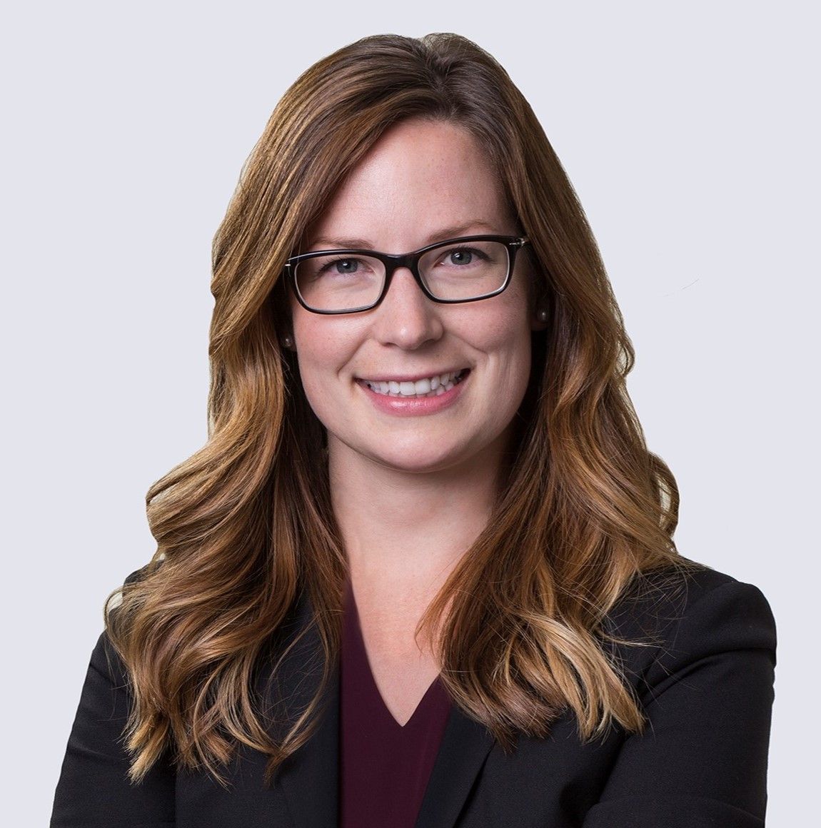 A woman wearing glasses and a black jacket is smiling for the camera.