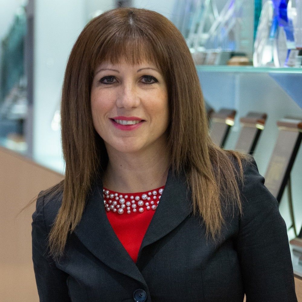 A woman wearing a black jacket and a red top smiles for the camera