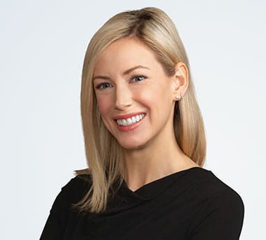 The woman is wearing a black shirt and smiling for the camera.