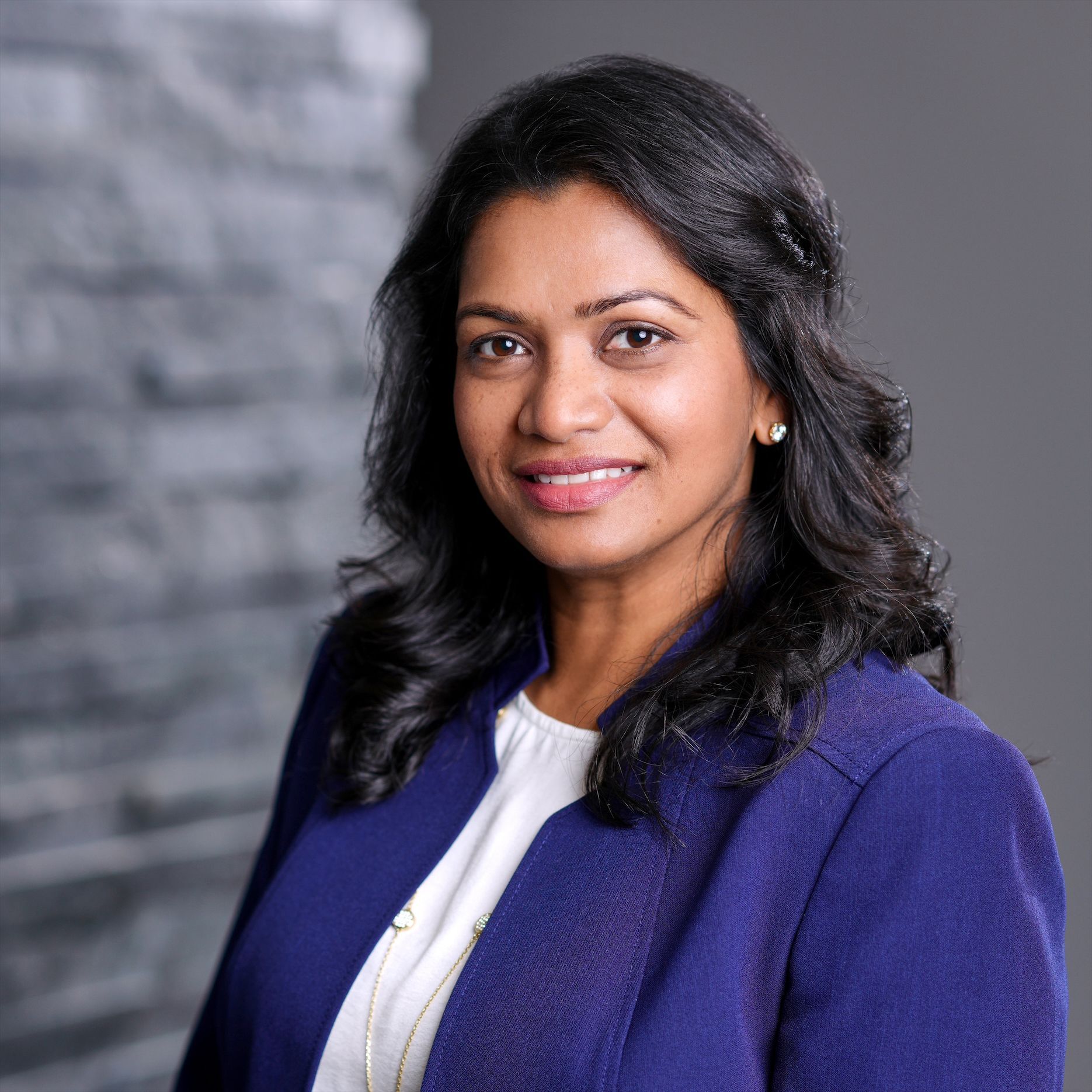 A woman in a blue jacket and white shirt is smiling for the camera.