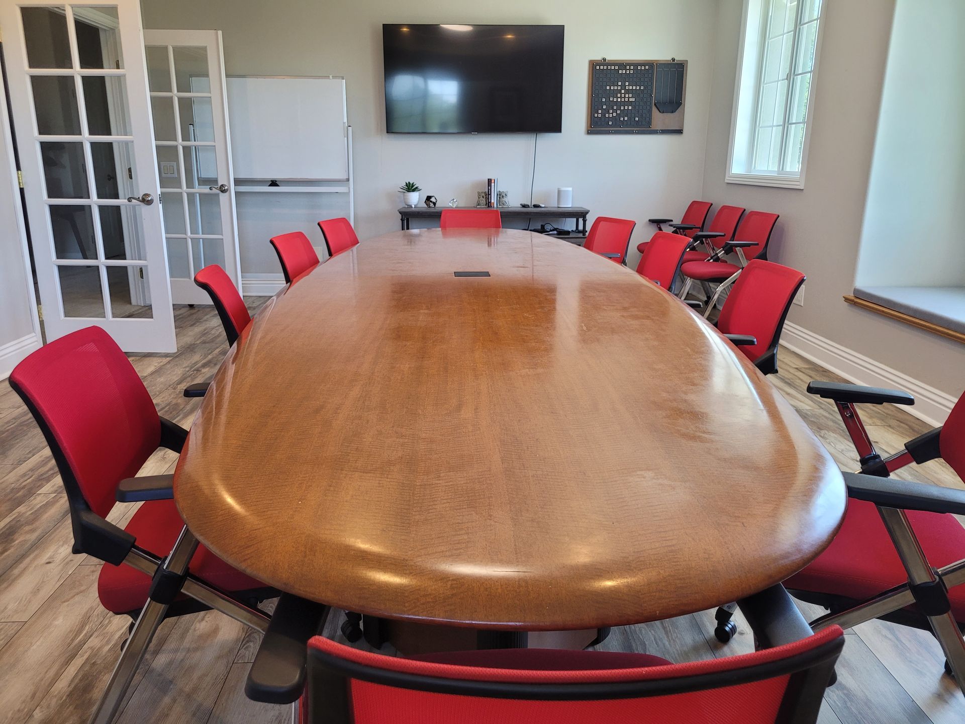 a conference room with a long wooden table and red chairs