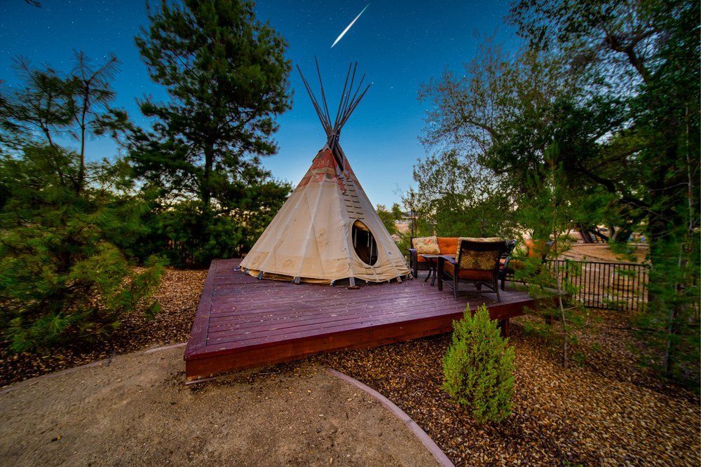 a teepee is sitting on top of a wooden deck surrounded by trees