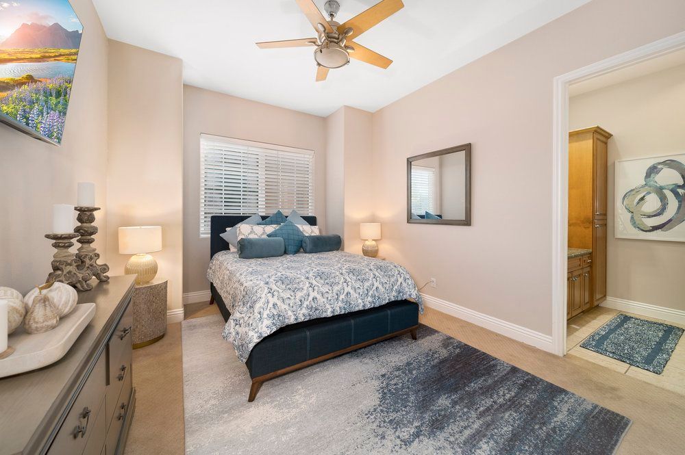 a bedroom with a bed, dresser, mirror and ceiling fan