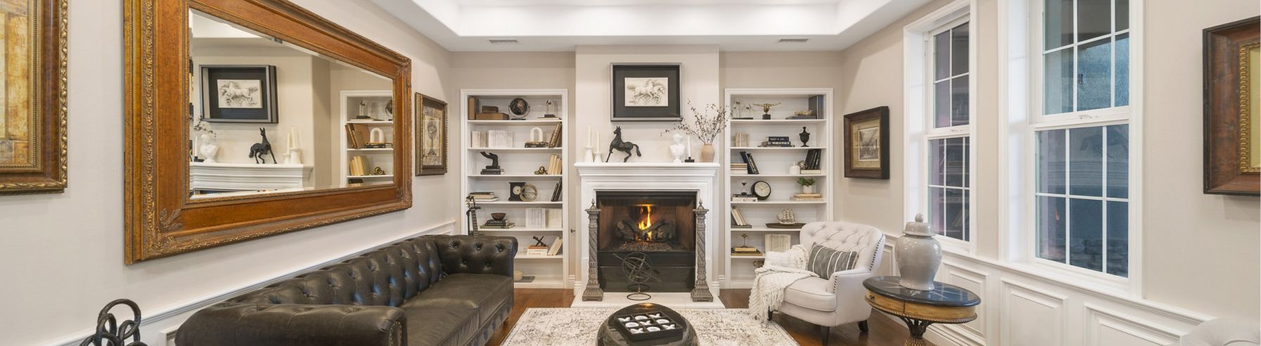 a living room with a fireplace, couch, chairs and mirrors
