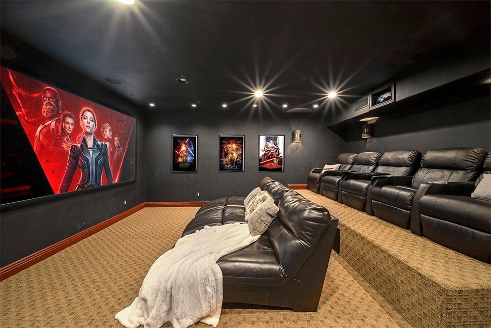 a home theater with a couch and chairs and a large screen