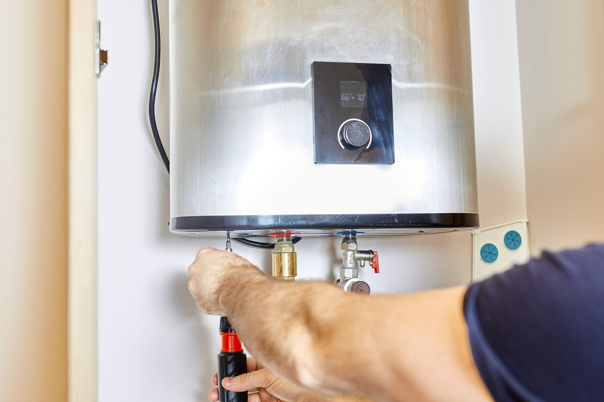 A technician servicing a tankless water heater with a screwdriver.