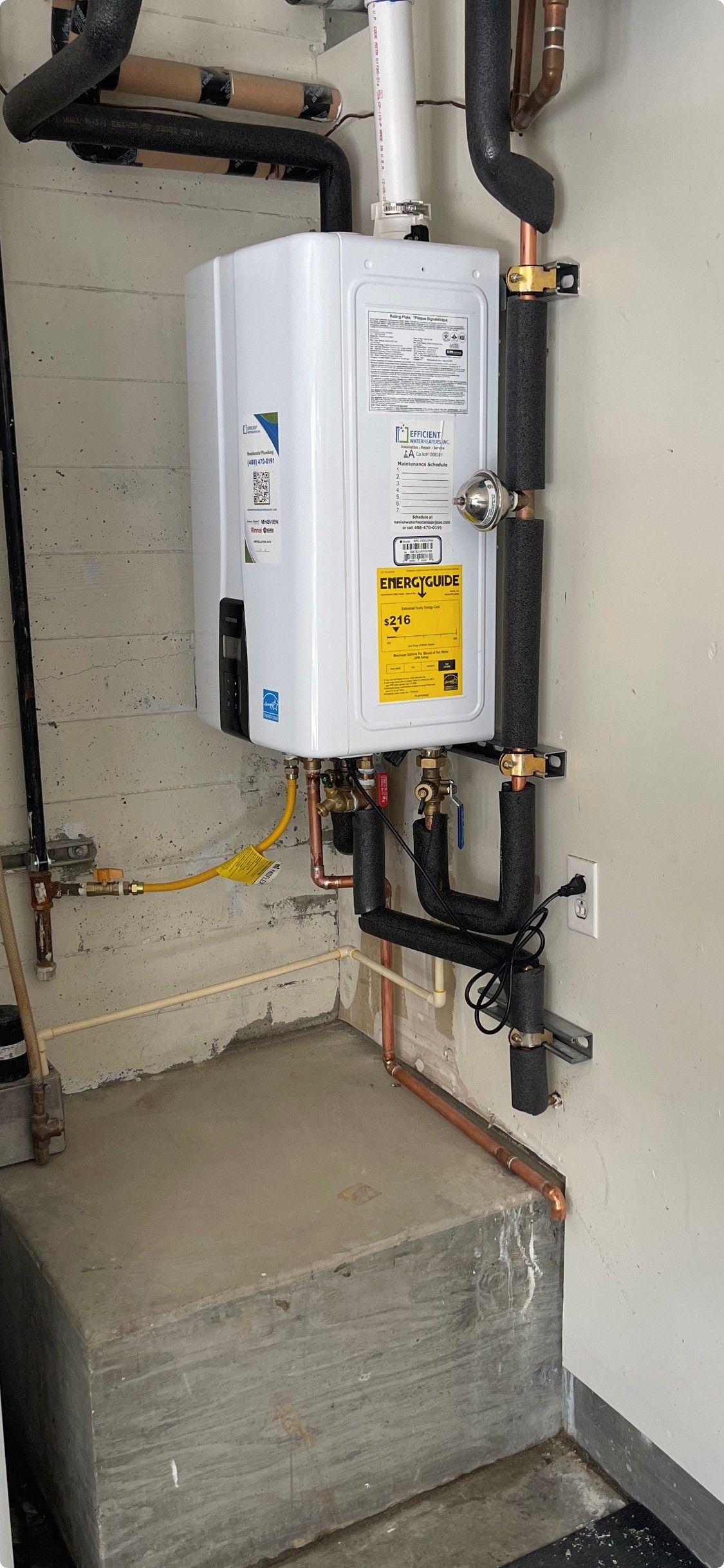 White wall-mounted boiler with black pipes in a utility room beside a concrete step.