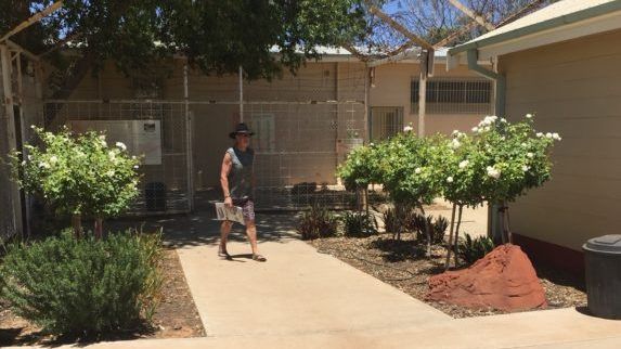 A woman is walking down a sidewalk in front of a building.