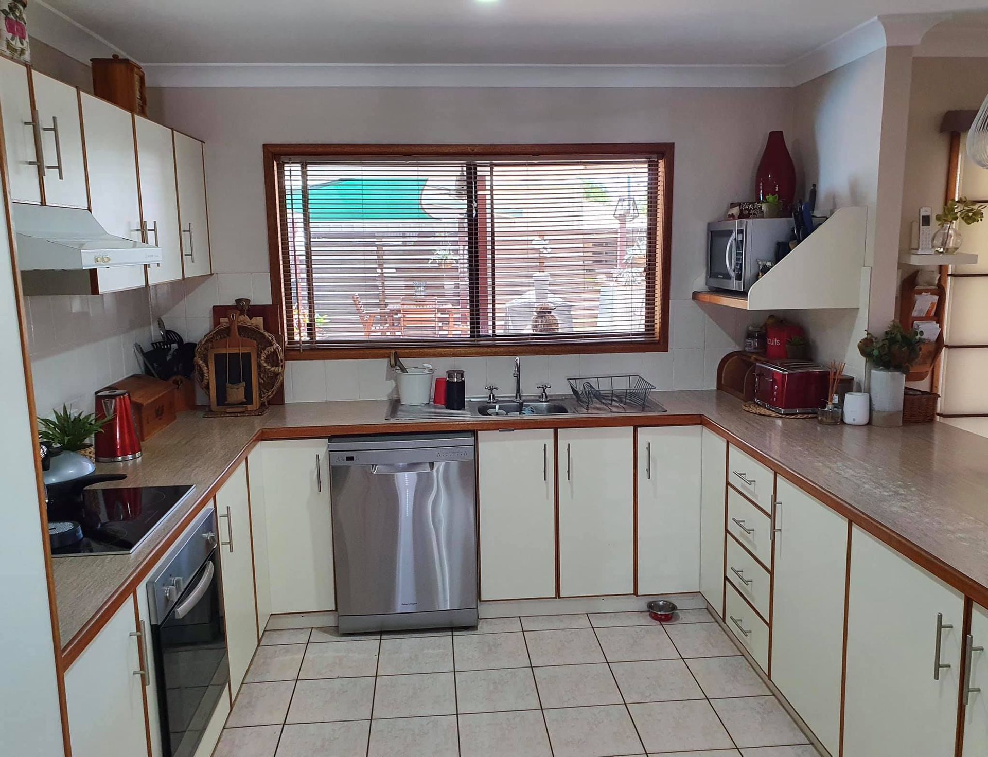 U-shaped kitchen with white cabinets, stainless steel appliances, and a window overlooking an outdoor area.