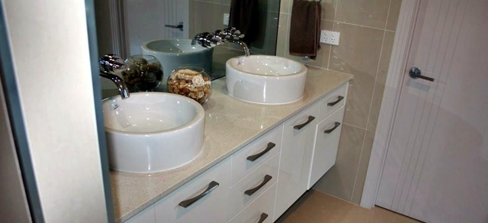 Bathroom with two white bowl sinks on a white cabinet, with a mirror, and a door.