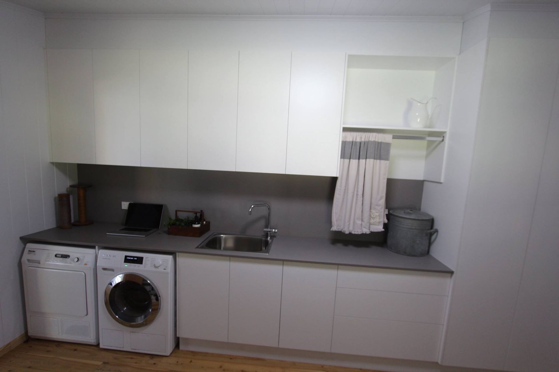 Laundry room with white cabinets, gray countertop, washer, dryer, and sink.