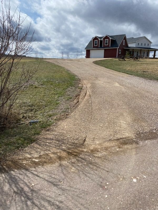 A wide, unpaved path under construction through a grassy field, featuring a roll of black landscape fabric and soil piles.